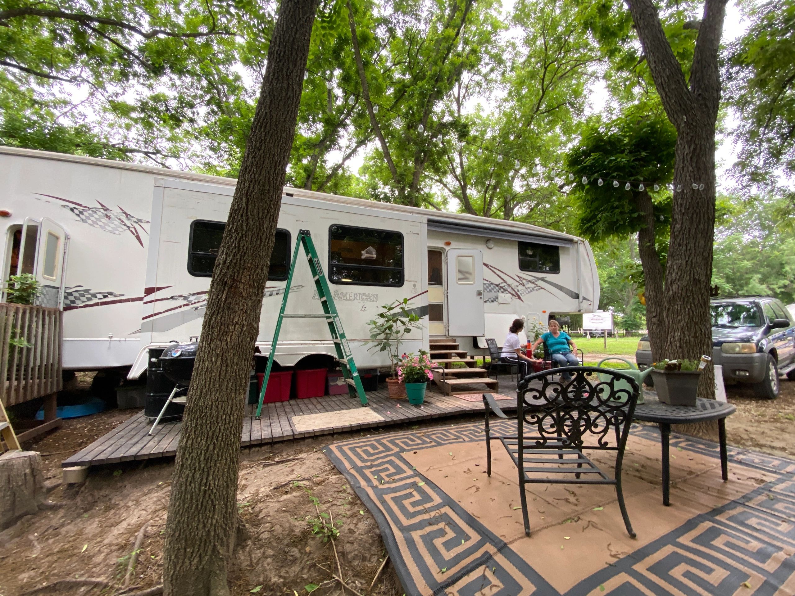 White RV trailer parked in wooded campground